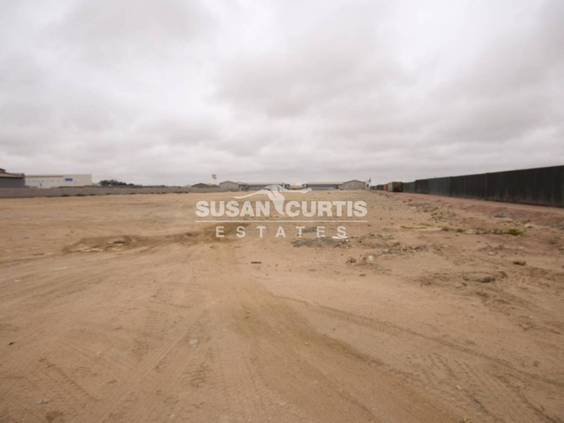 A wide-angle view of a vacant commercial land plot featuring cleared ground and perimeter fencing, suitable for development.