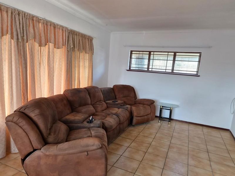 A living room featuring tiled flooring and dual window configurations, providing natural light and a functional layout for a comfortable seating area.