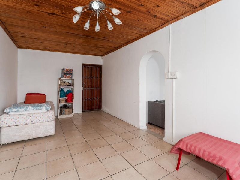 Living area featuring ceramic floor tiles, a timber tongue and groove ceiling, and an arched doorway leading to an adjacent space.