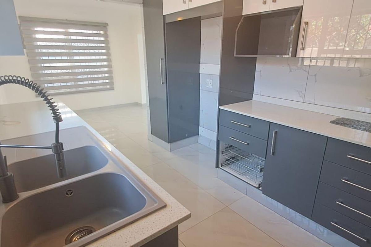 Modern kitchen featuring sleek grey and white cabinetry, quartz countertops, a double bowl sink with gooseneck faucet, and integrated extractor fan.