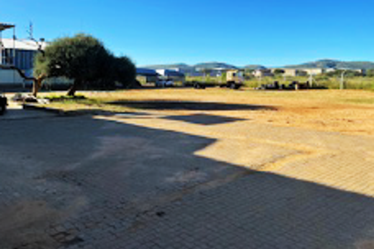 Expansive industrial yard area featuring paved sections and open ground, suitable for vehicle access or outdoor storage.