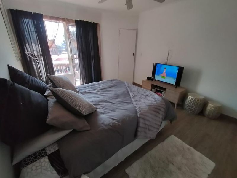 A bedroom featuring laminate flooring, a ceiling fan, and a sliding glass door providing access to an outdoor area.
