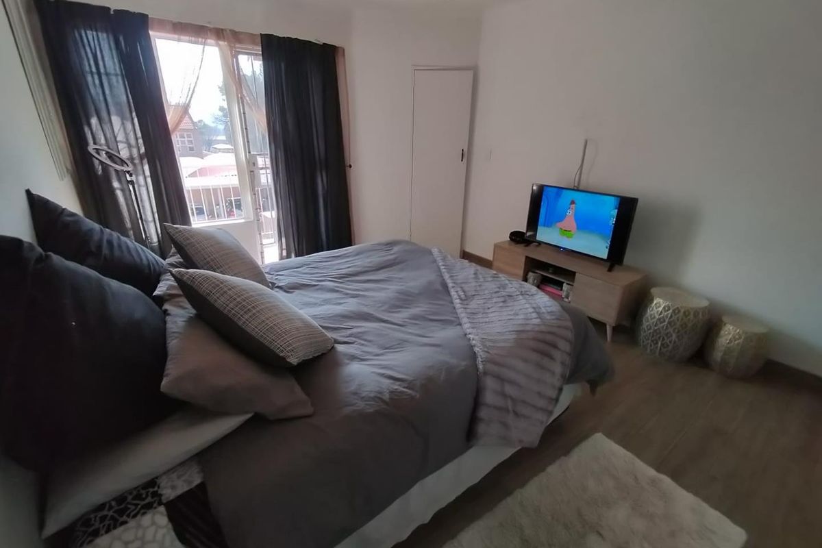 A bedroom featuring laminate flooring, a ceiling fan, and a sliding glass door providing access to an outdoor area.