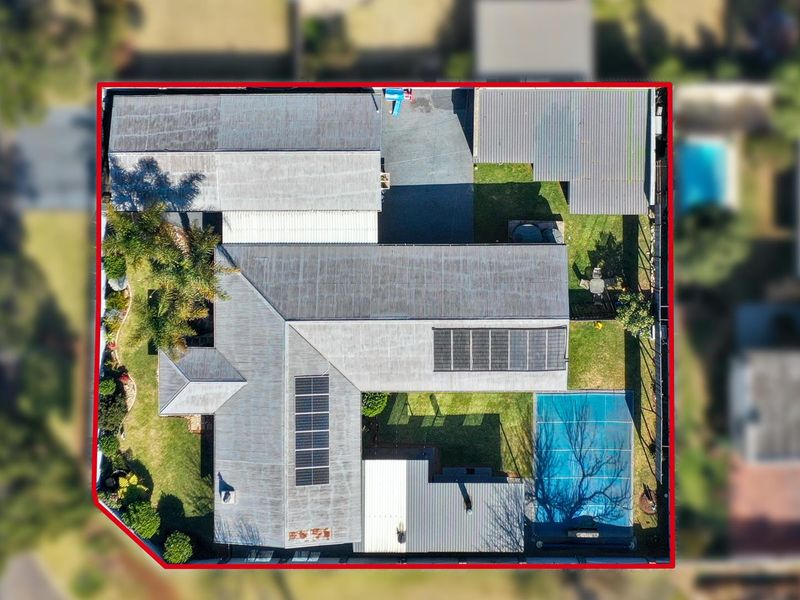 Aerial view of the property showing the roof layout, solar panel installation, swimming pool, and surrounding garden areas.