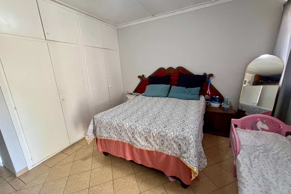A bedroom featuring built-in cupboards and tiled flooring, providing functional storage space.