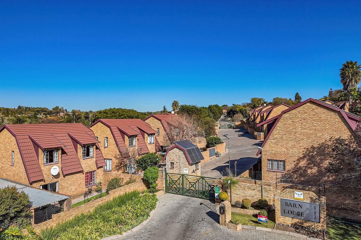 Aerial view of the Barn Lodge townhouse complex, featuring brick architecture, tiled roofs, secure gated entrance, and paved internal roadways.