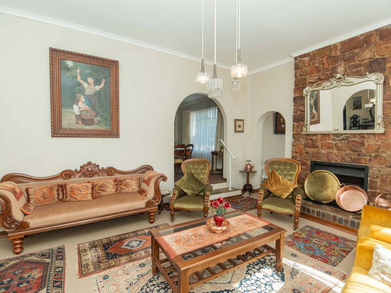A traditional living room featuring a prominent stone fireplace, decorative archways, and classic coving, offering a warm and character-filled space.
