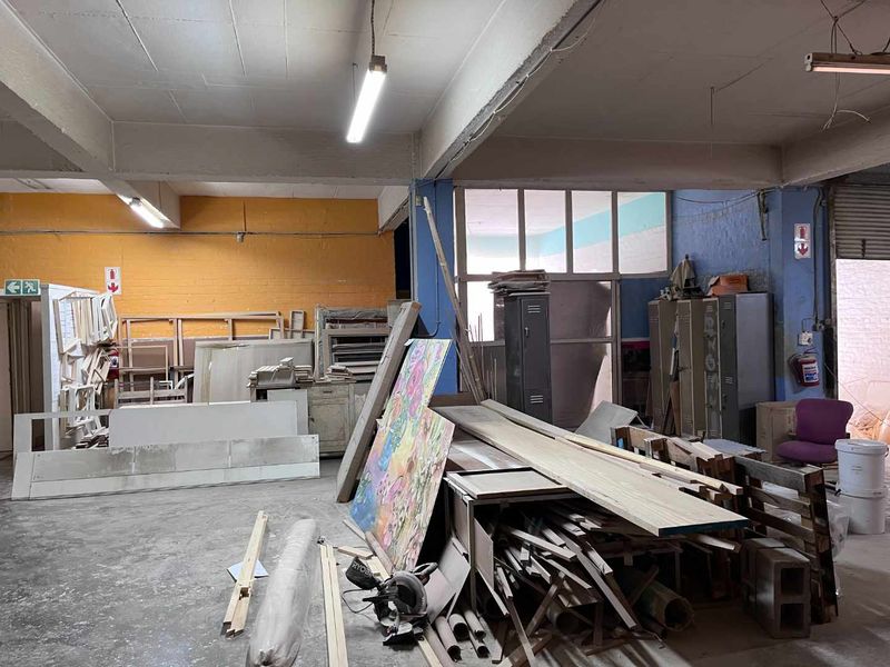 Industrial utility space featuring exposed concrete ceilings, fluorescent lighting, and metal storage lockers, suitable for workshop or storage use.