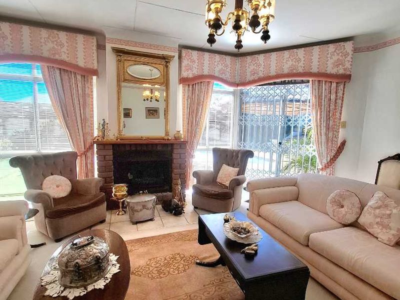A traditional living room featuring a brick fireplace, chandelier lighting, and sliding glass doors leading to an outdoor area.