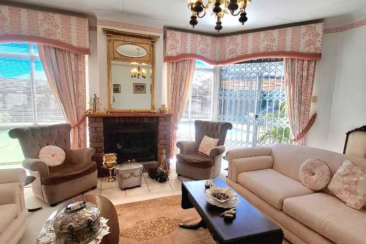 A traditional living room featuring a brick fireplace, chandelier lighting, and sliding glass doors leading to an outdoor area.