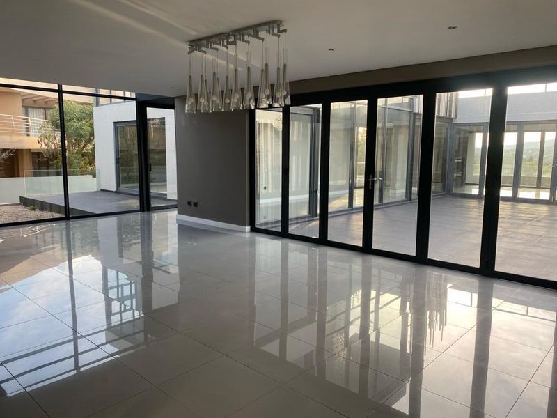 Spacious, modern living area featuring large format polished floor tiles and extensive floor-to-ceiling stacking doors that provide seamless indoor-outdoor flow.
