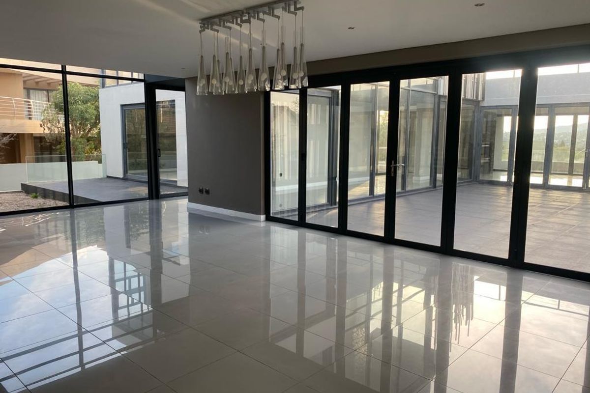 Spacious, modern living area featuring large format polished floor tiles and extensive floor-to-ceiling stacking doors that provide seamless indoor-outdoor flow.