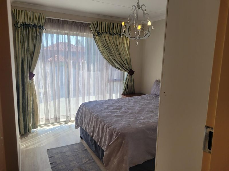 A bedroom featuring laminate flooring and a sliding glass door providing natural light and access to the exterior.