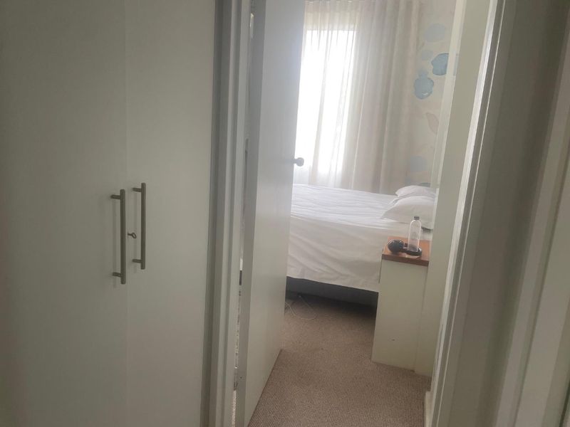 A view into a bedroom featuring built-in wardrobe storage and carpeted flooring, viewed from an adjacent hallway.