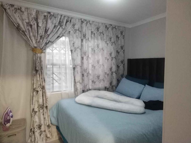 A compact bedroom featuring neutral wall finishes and a window with curtain treatments.