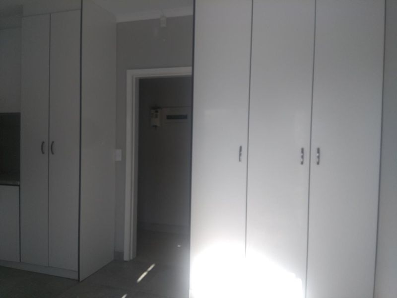 A clean hallway featuring ample built-in storage cupboards and neutral tiled flooring, providing a functional transition space within the home.