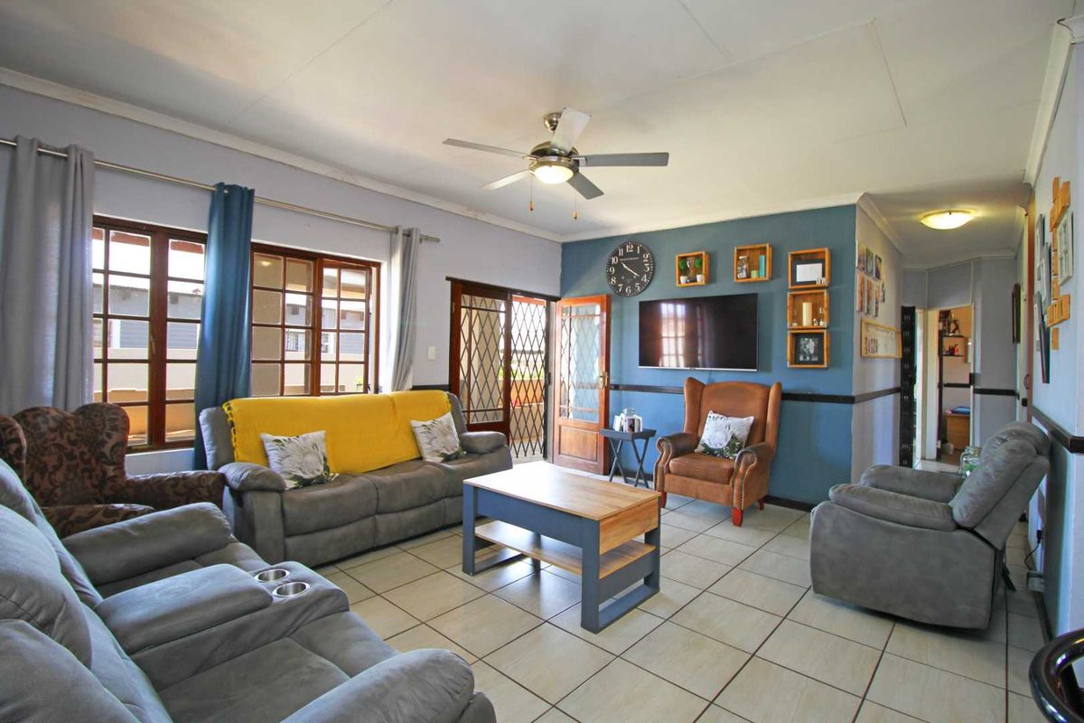 A spacious living room featuring tiled flooring, a ceiling fan, and a feature wall, providing a comfortable and functional family living space.
