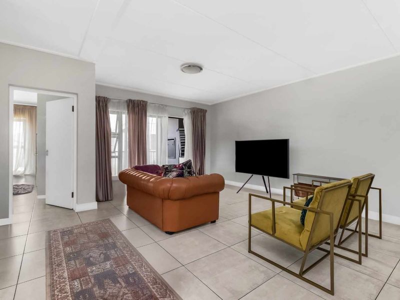 A bright and spacious living room featuring neutral tiled flooring and large sliding glass doors that provide access to an adjoining area.