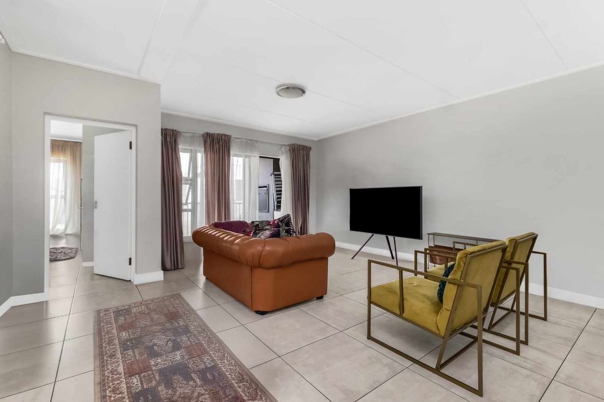 A bright and spacious living room featuring neutral tiled flooring and large sliding glass doors that provide access to an adjoining area.