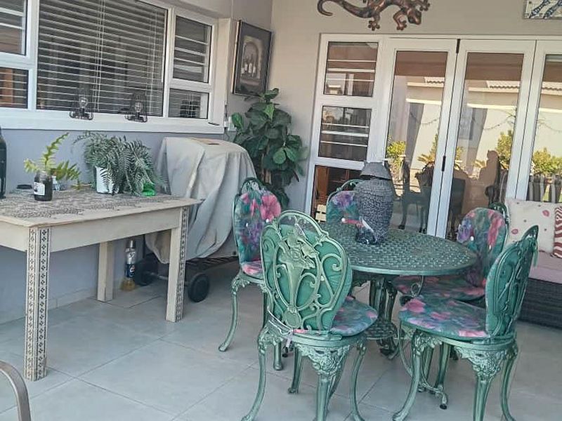 A covered patio area featuring tiled flooring, large sliding glass doors, and aluminium window frames, providing a functional outdoor living space.