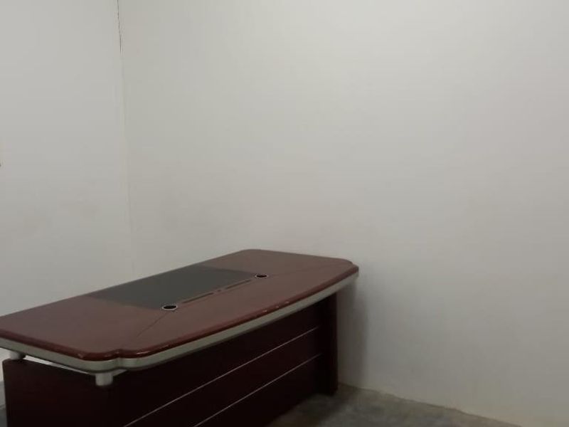 A simple, functional office space featuring plain walls and a basic electrical outlet.