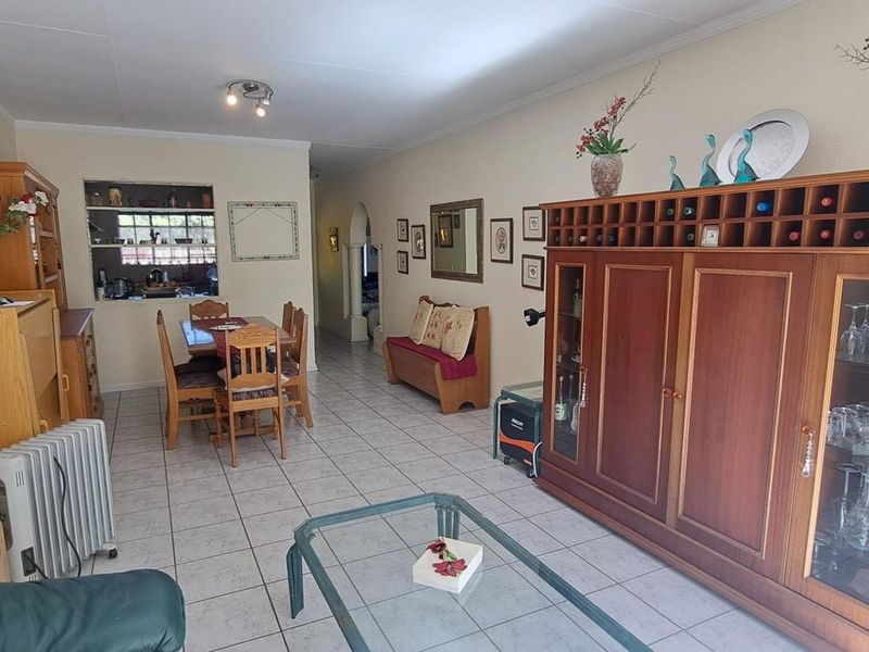 Open-plan living and dining area featuring neutral tiled flooring and a convenient pass-through window connecting to the kitchen space.