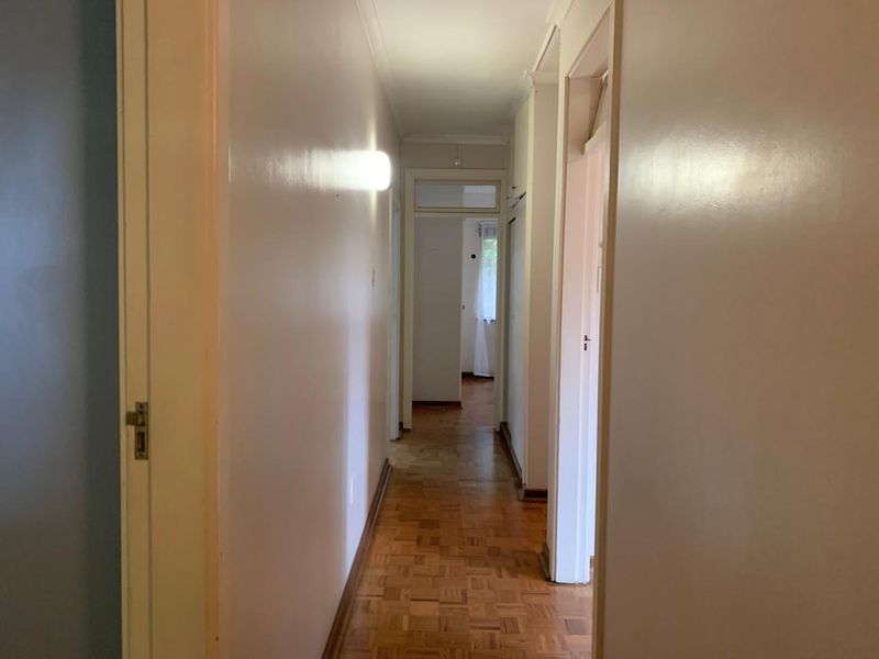 A functional hallway featuring classic parquet flooring and neutral wall finishes, providing access to multiple rooms within the home.