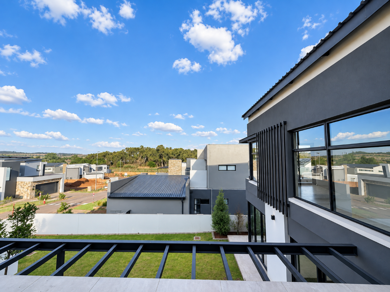 Modern upper-level balcony featuring a sleek metal pergola, large glass windows, and views over the surrounding residential estate.