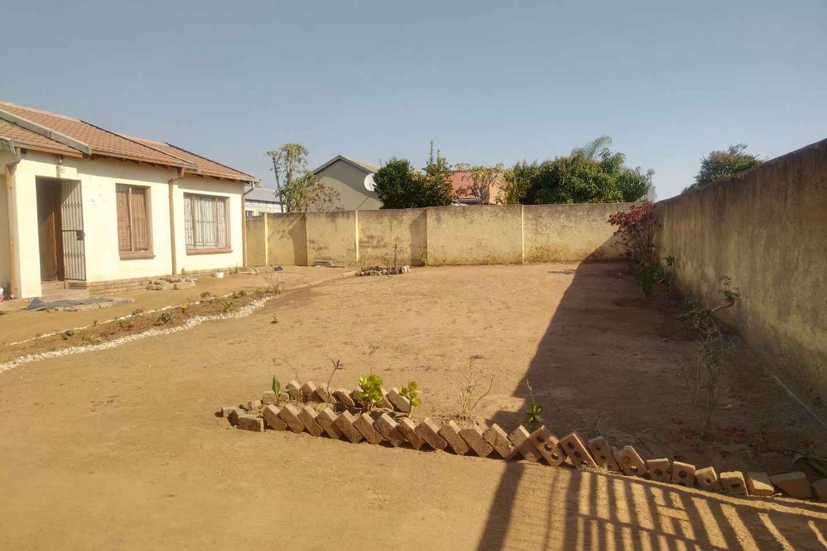 A spacious rear yard featuring high boundary walls and a large, undeveloped sandy area ready for landscaping or outdoor improvements.