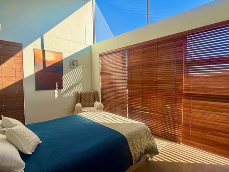 Bright bedroom featuring a high raked ceiling, clerestory windows for natural light, and timber venetian blinds.