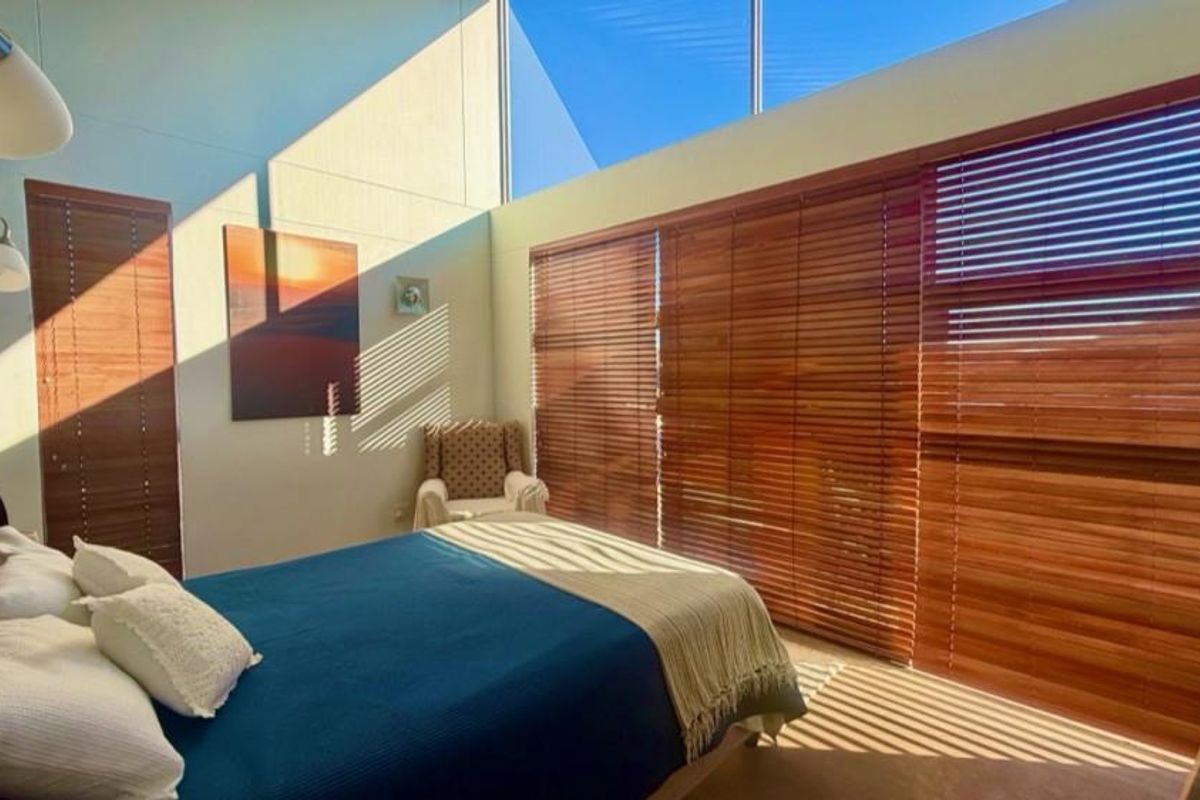 Bright bedroom featuring a high raked ceiling, clerestory windows for natural light, and timber venetian blinds.