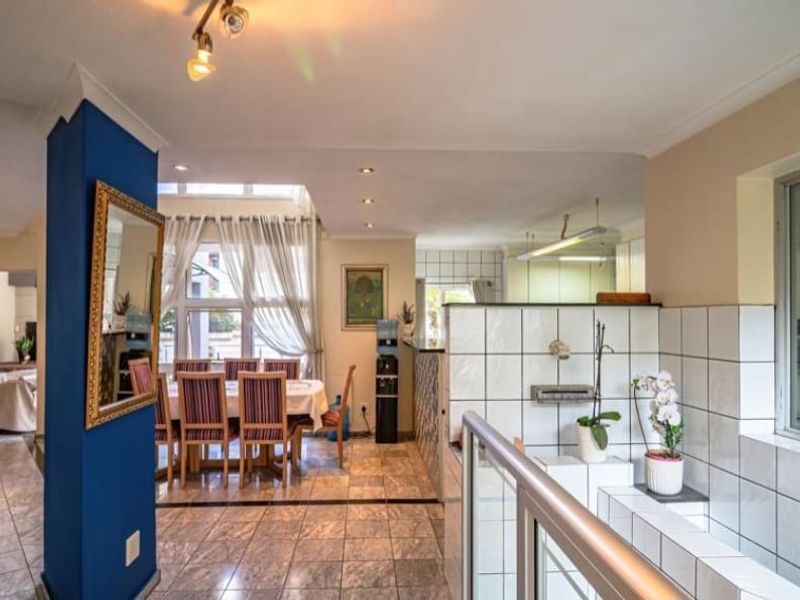An open-plan living and dining area featuring tiled flooring, recessed lighting, and a prominent structural column, creating a connected and functional living space.