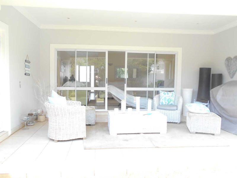 A covered patio area featuring tiled flooring, recessed ceiling lighting, and large sliding glass doors providing access to the interior living space.