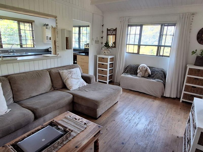 Open plan living area featuring timber flooring, wall paneling, and a convenient pass-through window connecting to the kitchen space.