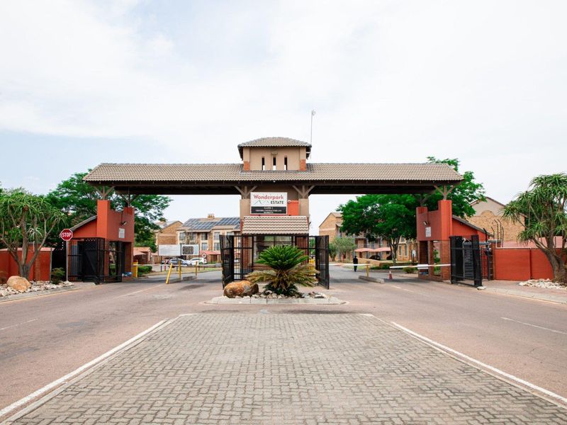 The main entrance gatehouse of Wonderpark Estate, featuring a secure access point with boom gates, paved driveway, and perimeter security infrastructure.
