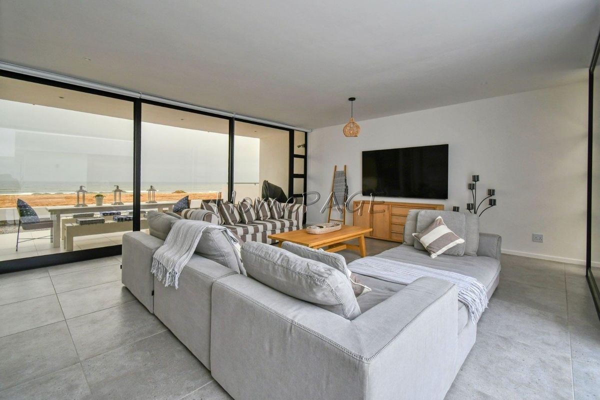 Modern open-plan living area featuring large sliding glass doors that open onto a patio with scenic ocean views.