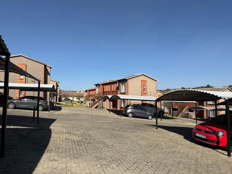 Exterior view of an apartment complex featuring paved parking areas and covered carports for residents.