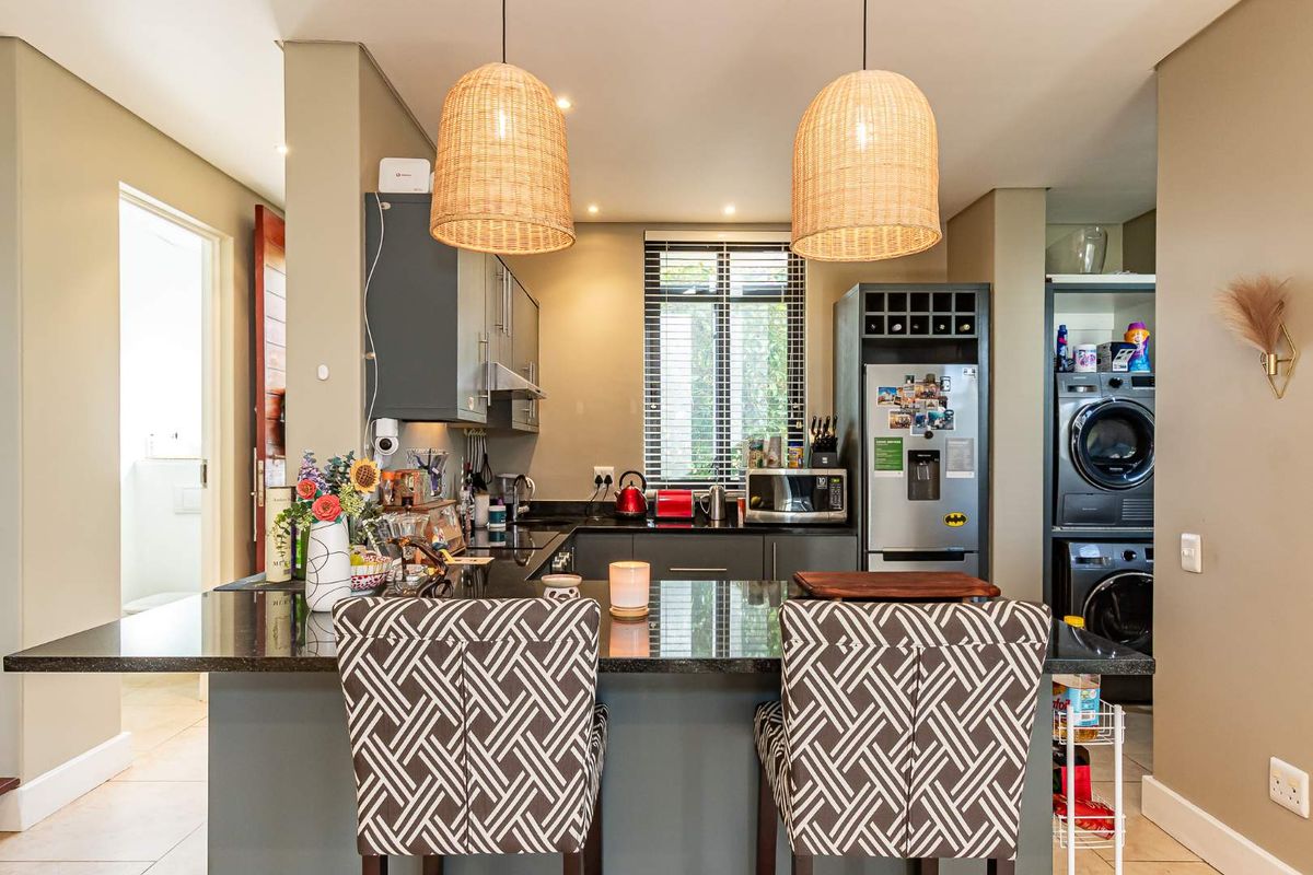 Modern kitchen featuring dark cabinetry, granite countertops, a breakfast bar, and integrated laundry facilities, offering a functional and stylish cooking and utility space.