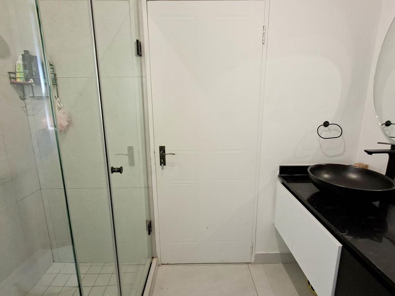 Modern bathroom featuring a glass-enclosed shower, a floating vanity with a black vessel sink, and contemporary black fixtures.