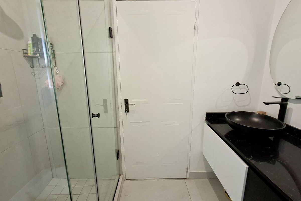Modern bathroom featuring a glass-enclosed shower, a floating vanity with a black vessel sink, and contemporary black fixtures.