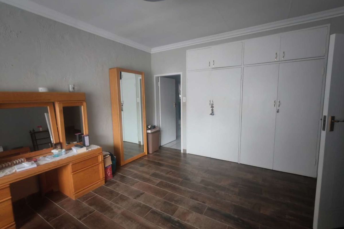 A bedroom featuring built-in cupboards, tiled flooring, and crown molding, providing a functional and neutral living space.