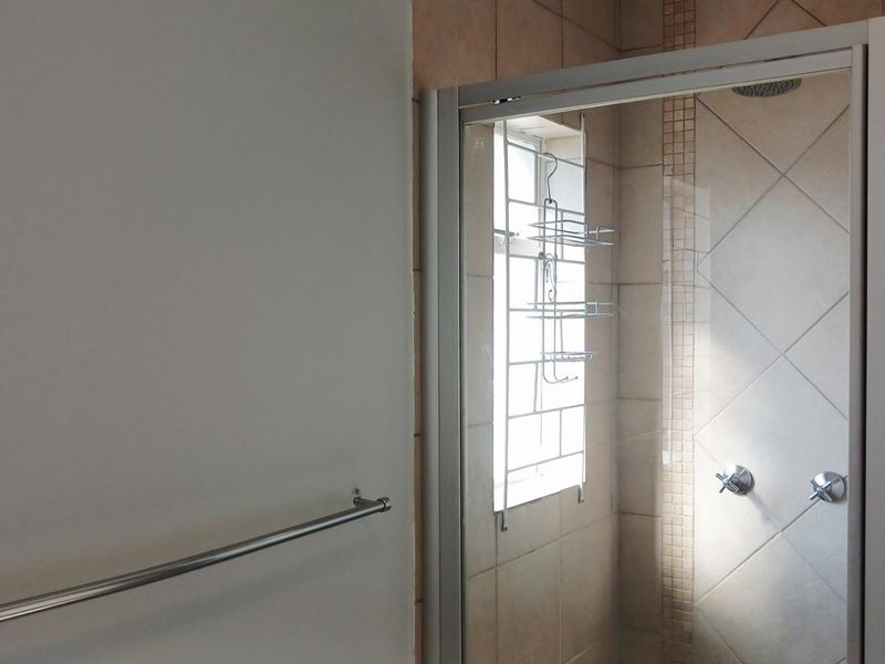 A functional bathroom featuring a tiled shower enclosure with a glass door and a wall-mounted towel rail.