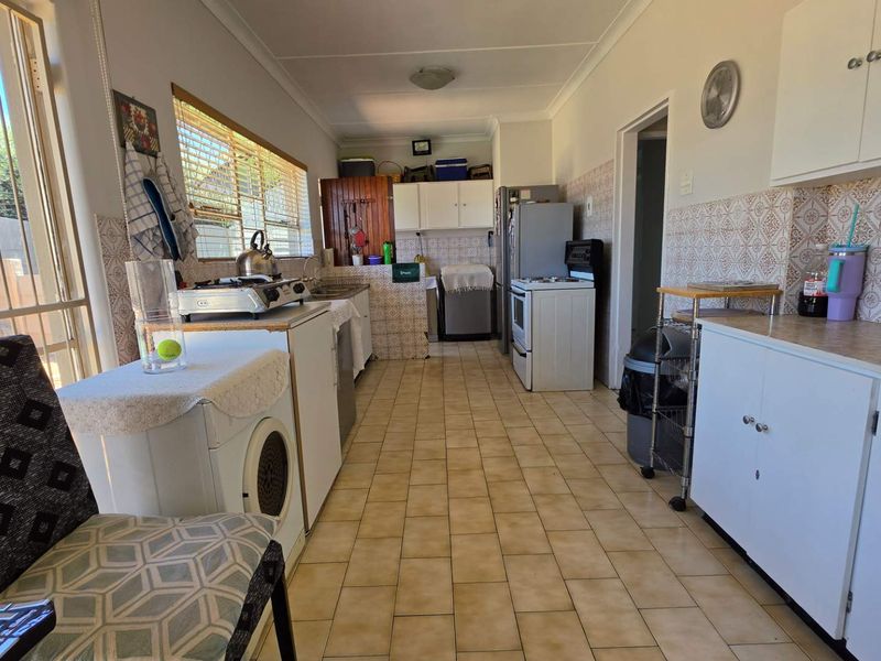 A functional kitchen featuring tiled flooring, built-in cabinetry, laminate countertops, and a tiled backsplash, offering a dated aesthetic ready for modernization.
