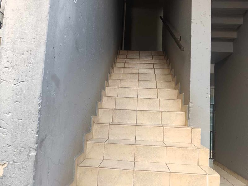A functional staircase with tiled steps and a metal handrail, showing signs of wear on the surrounding walls.