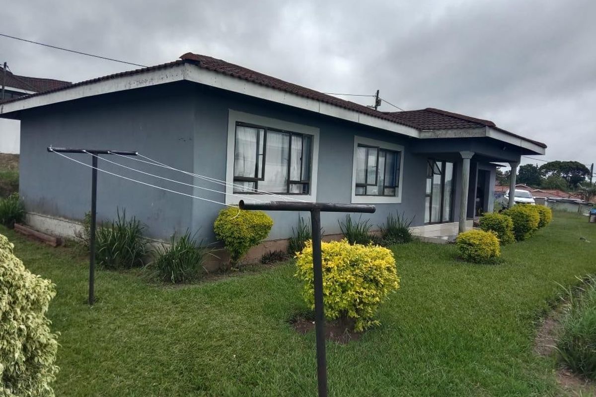 Rear view of the house showing the exterior facade, tiled roof, and surrounding garden area.