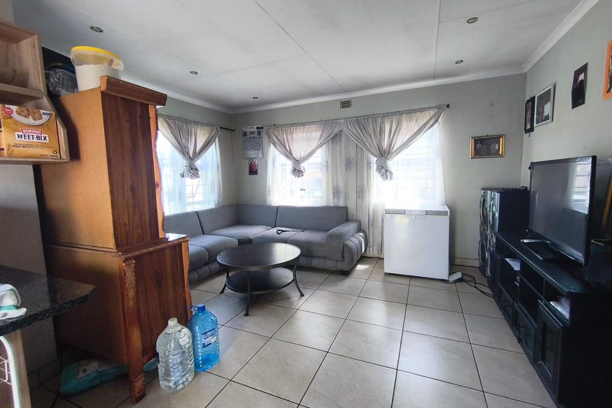 A living room featuring tiled flooring and recessed ceiling lighting, with window security bars installed for added safety.
