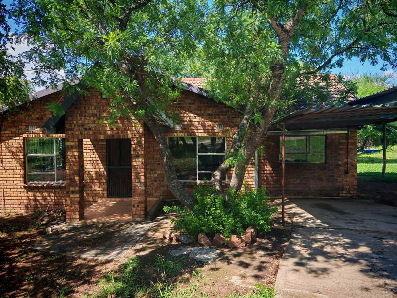 Front view of a face brick house featuring a tiled roof, aluminum window frames, and an attached carport with a concrete driveway.
