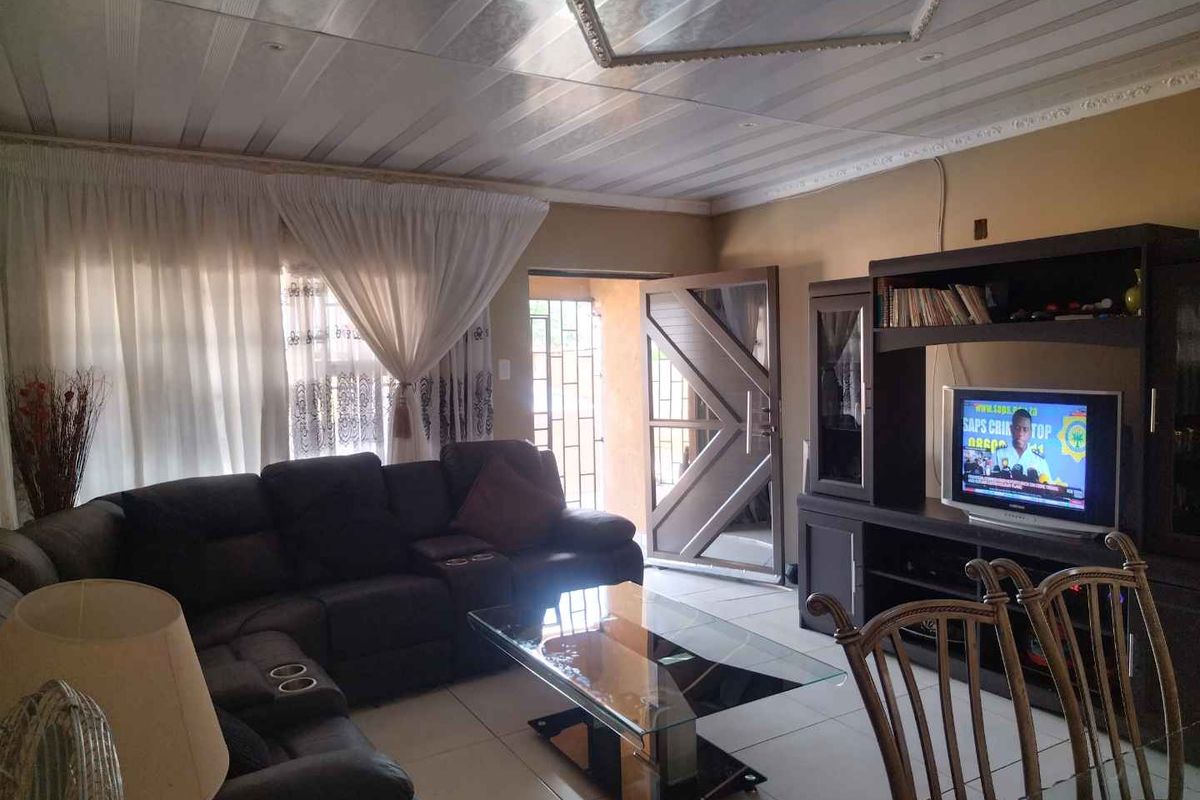 A living room featuring tiled flooring, a decorative ceiling, and a security gate at the entrance.