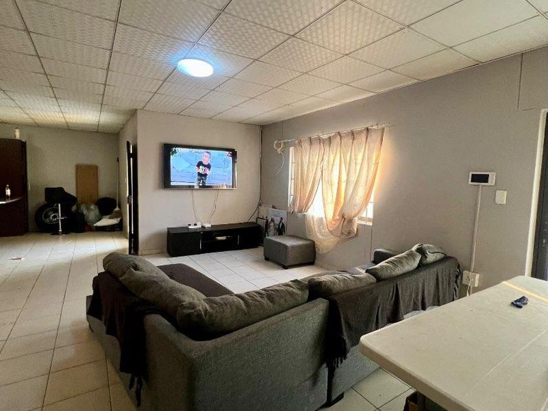 A living room featuring ceramic floor tiles and a suspended ceiling, providing a functional space with potential for cosmetic updates.