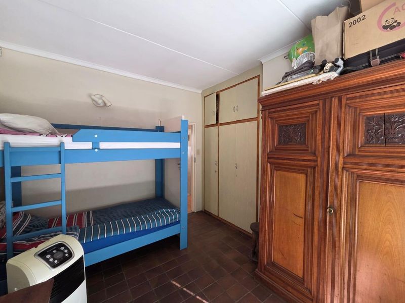 A bedroom featuring built-in cupboards and tiled flooring, offering a functional space that could benefit from cosmetic updates to modernize the interior finishes.